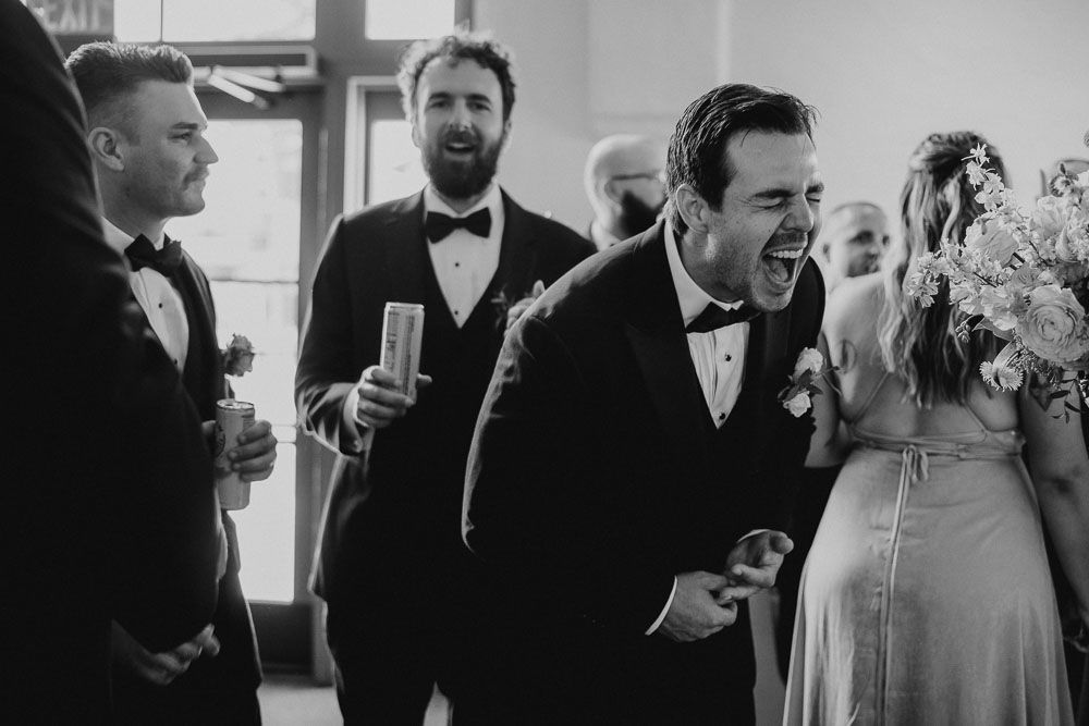 Wedding guests in formal attire sharing laughter during reception celebration.