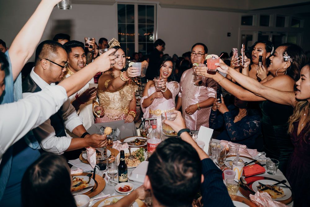 Wedding guests raising their glasses in a celebratory toast during the reception dinner.