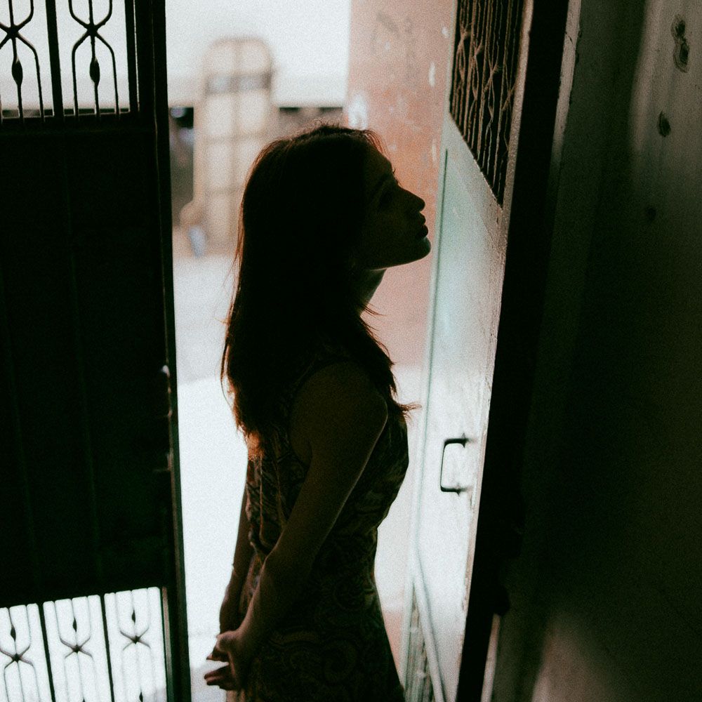 Dramatic silhouette portrait in a doorway with iron gate details.