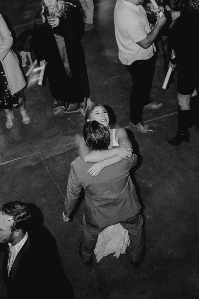 Black and white photo of couples dancing closely at a dimly lit reception.