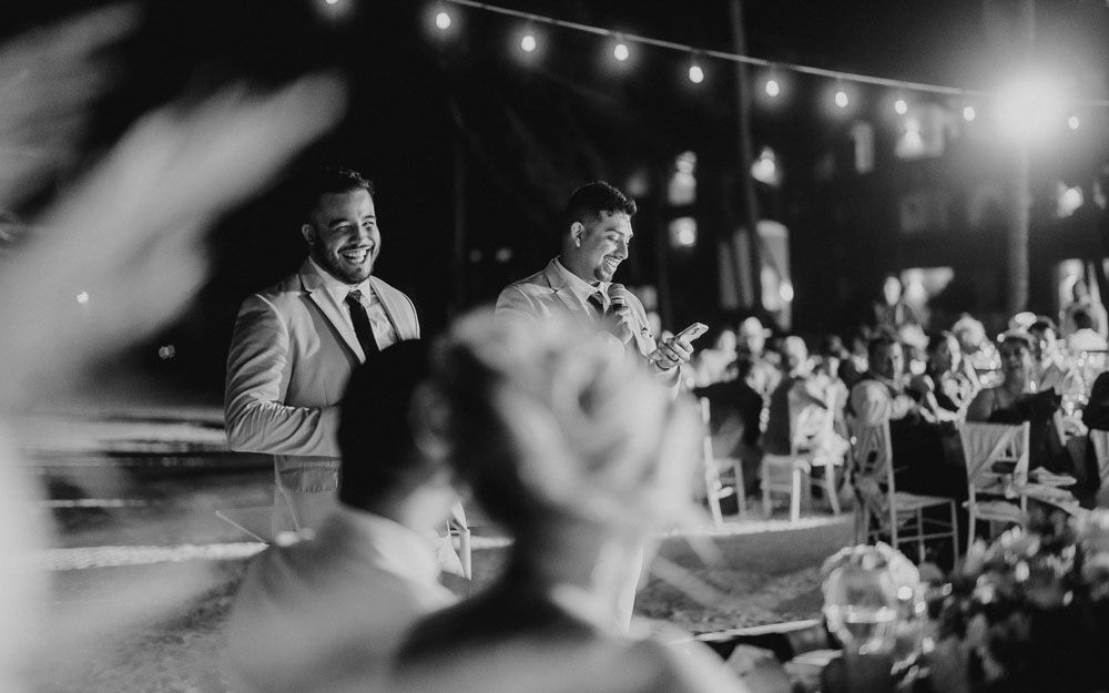 Wedding reception guests enjoying the celebration under string lights at night.