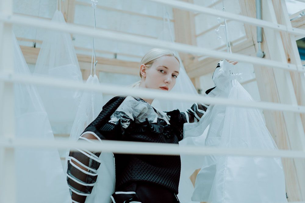 Artistic fashion portrait with white architectural elements creating geometric composition.