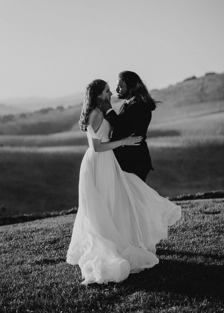 Black and white photos of a couple dancing on a grassy hillside in wedding attire.
