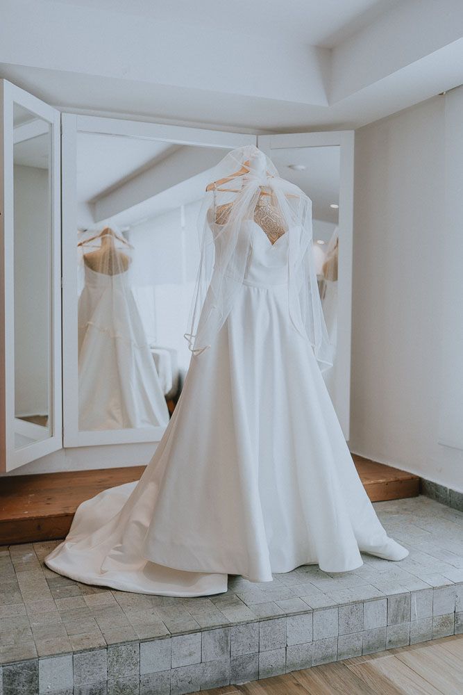Collection of elegant white wedding dresses displayed on hangers in a bright room.