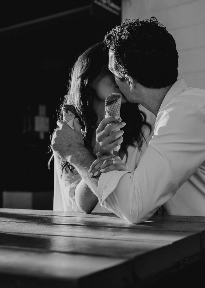 Black and white intimate portrait of couple sharing ice cream cone.