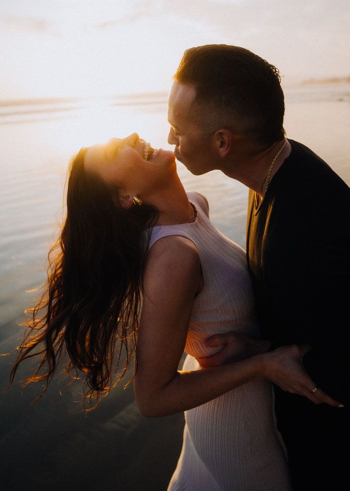 An intimate sunset beach portrait session with warm golden light filtering through.