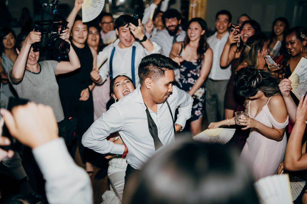 Wedding guests dance and celebrate on crowded reception dance floor.