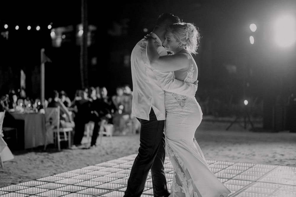 Couple sharing an intimate first dance on a lit dance floor at their wedding reception.