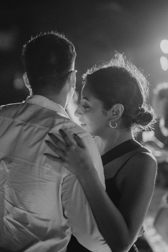 A romantic couple slow dancing together in black and white with dramatic lighting.
