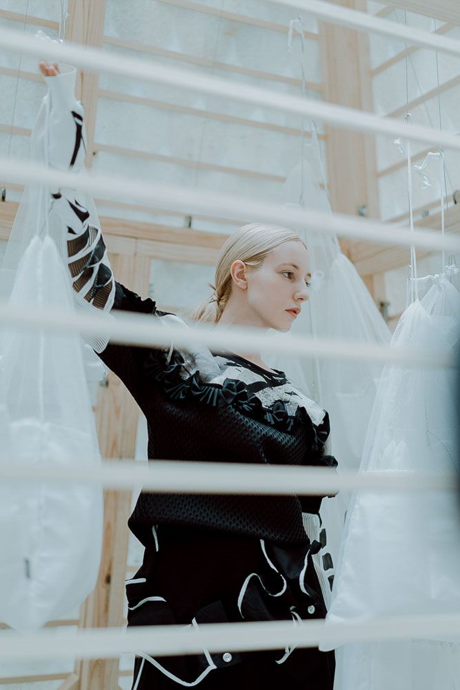 Fashion portrait with geometric white scaffolding creating dramatic framing effect.