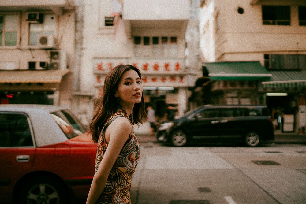Urban street fashion photography with vintage cars and city buildings in the background.