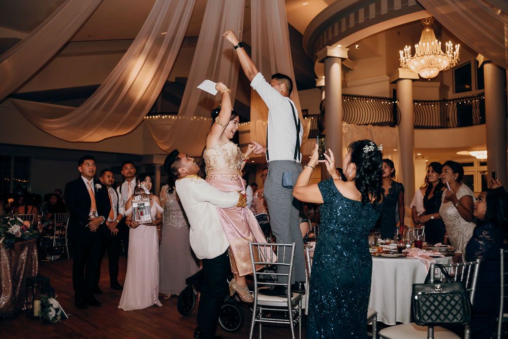 Energetic wedding reception scene with guests lifted high during a dance celebration.