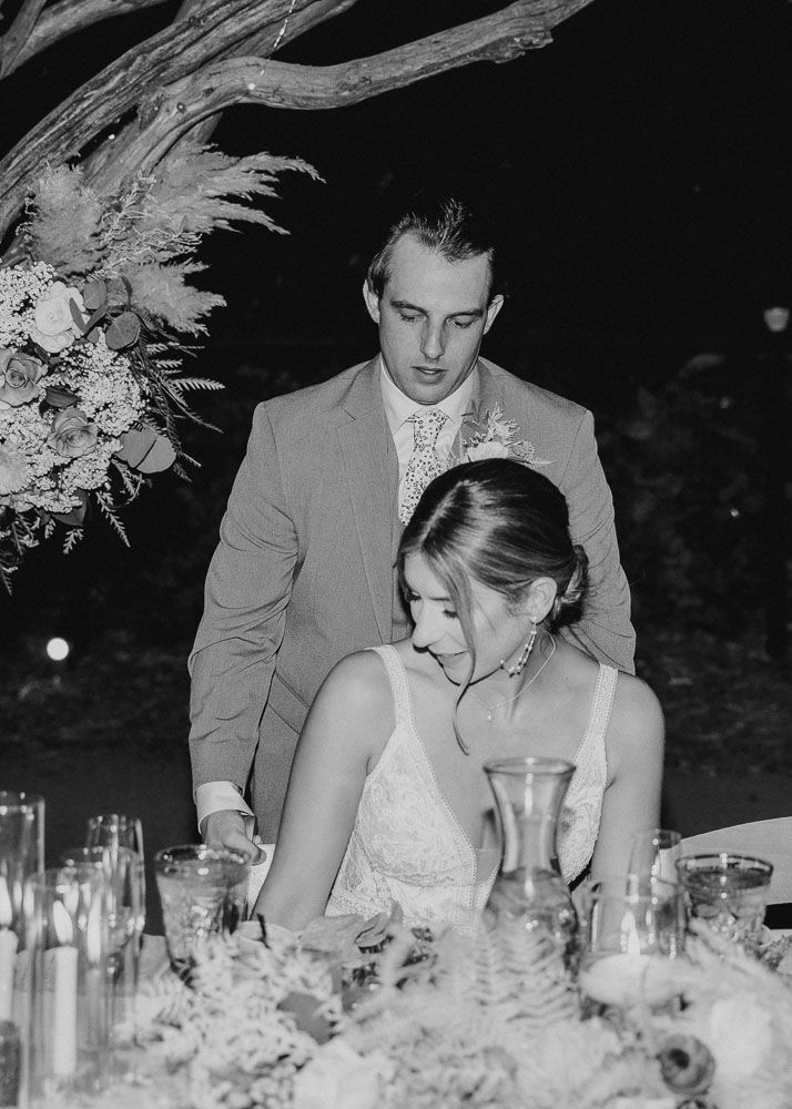 Black and white candid moment at elegant outdoor reception dinner.