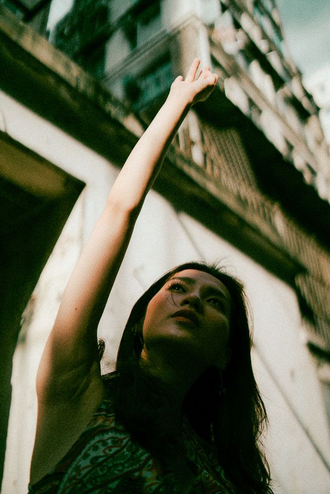 Artistic upward angle portrait with dramatic lighting against an urban backdrop.