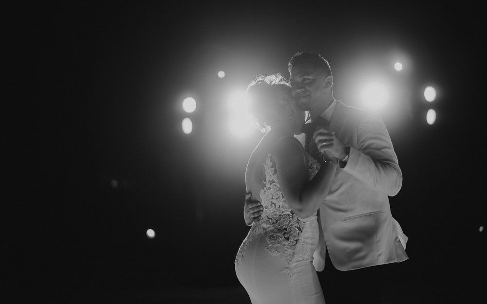 Black and white romantic dance moment at a wedding reception with soft lighting.