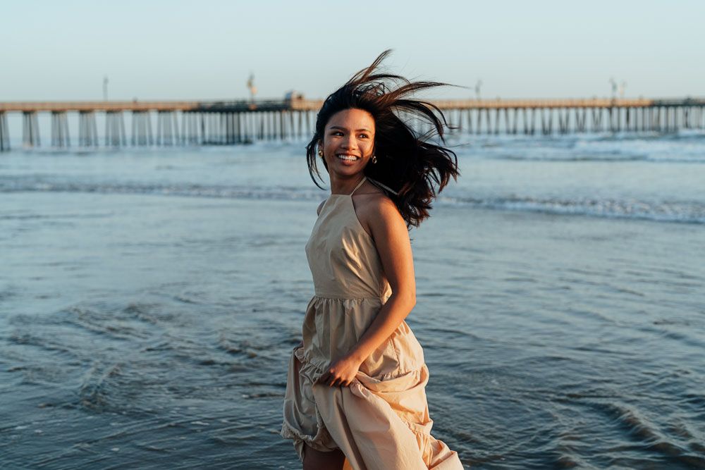 Dynamic beach portrait with flowing dress and hair caught in ocean breeze.