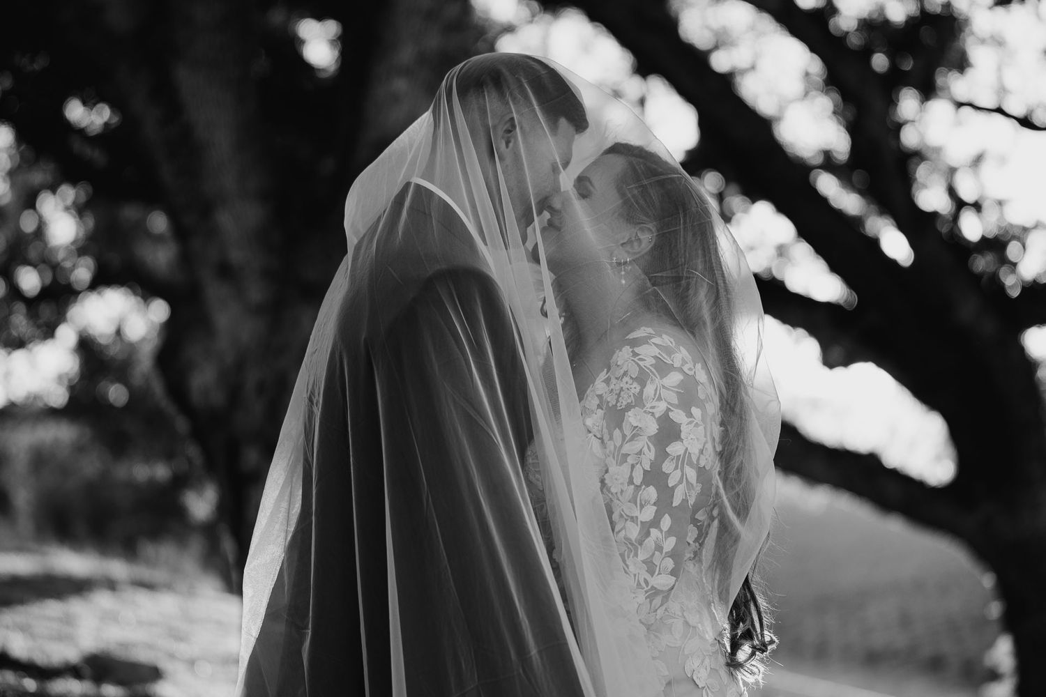Intimate black and white moment of couple under wedding veils.