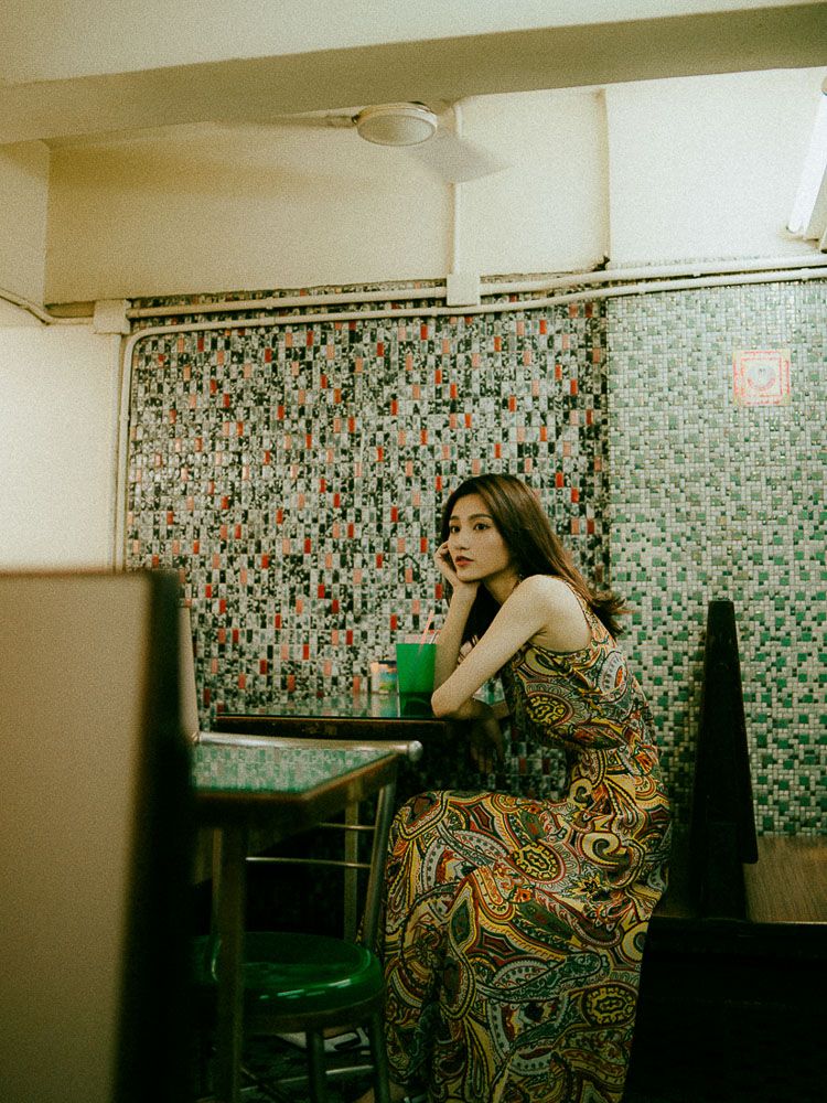 Moody portrait in vintage diner setting with mosaic walls and retro furniture.