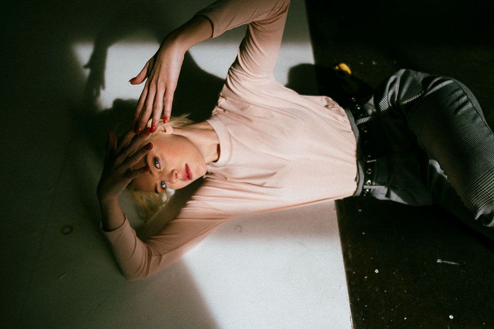 Artistic portrait of a person lying down in dramatic lighting wearing a light colored shirt.
