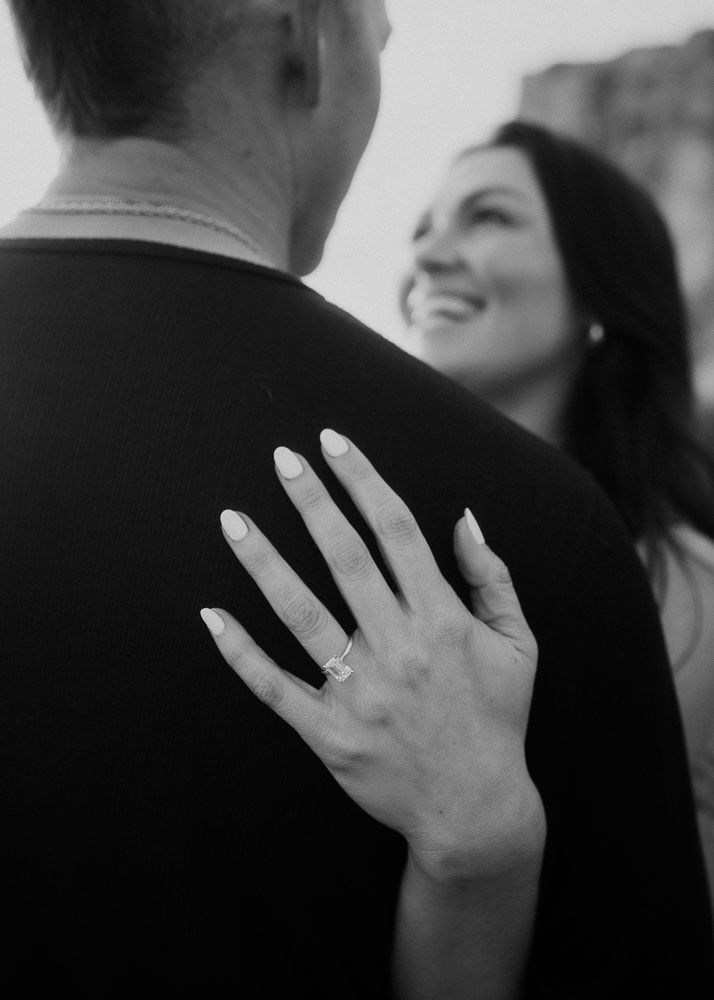 Close-up black and white shot showing hands tenderly embracing during an intimate moment.