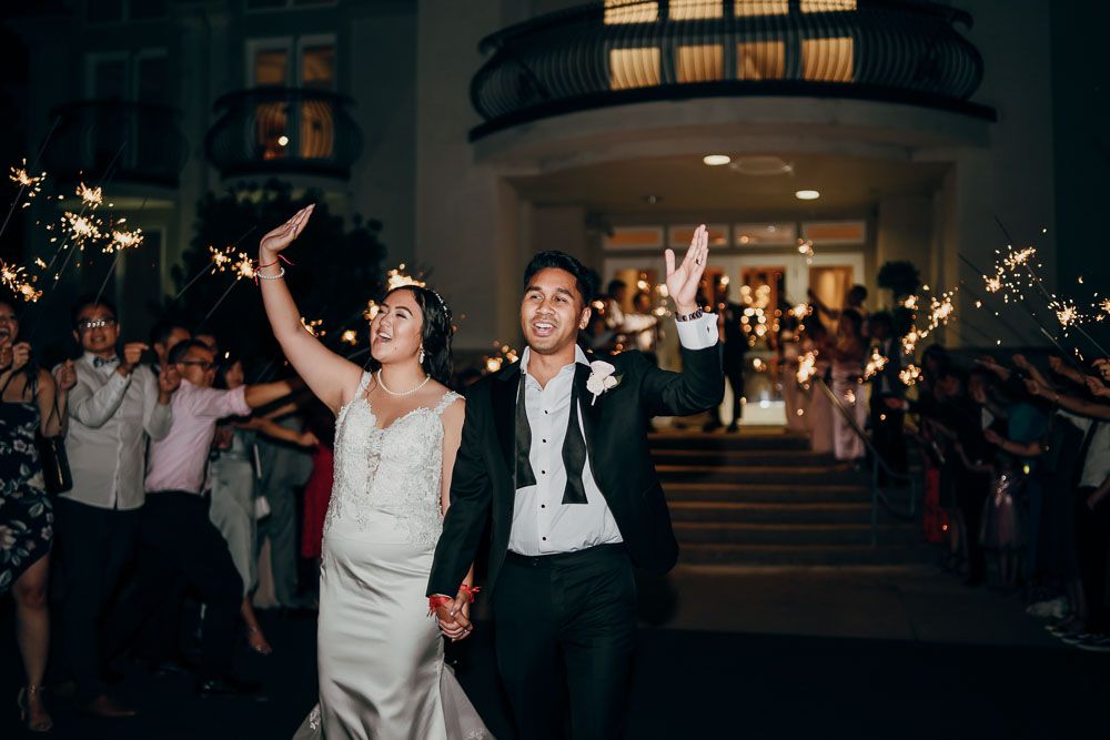 Newlyweds celebrate during sparkler exit outside venue.