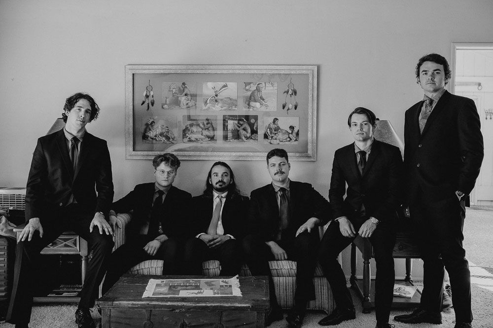 Wide angle black and white shot of groomsmen relaxing before the ceremony.
