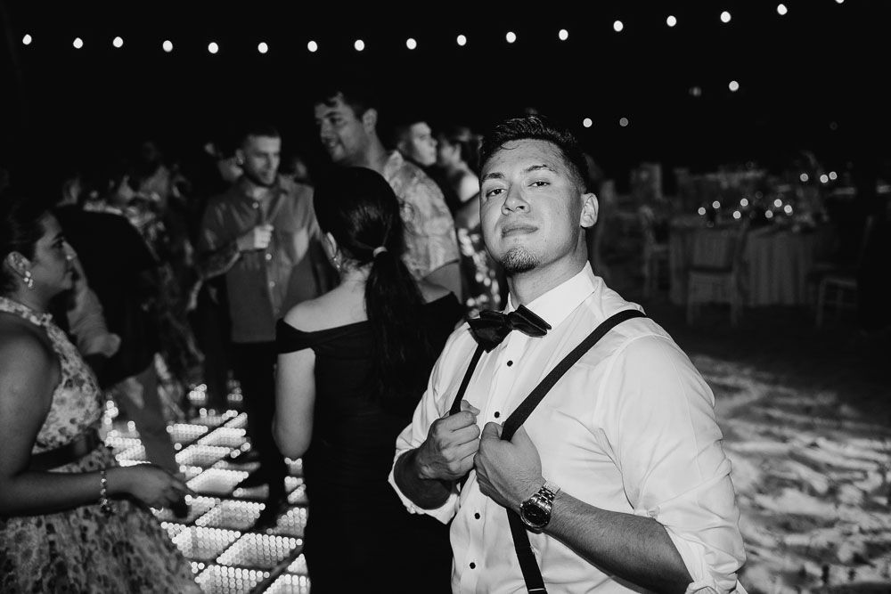 Black and white portrait of guest in suspenders at evening reception.