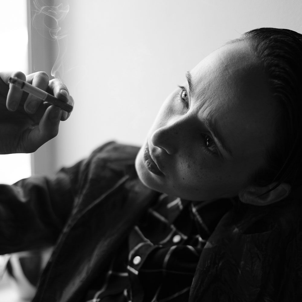 Artistic black and white photo showing side profile with rising cigarette smoke.