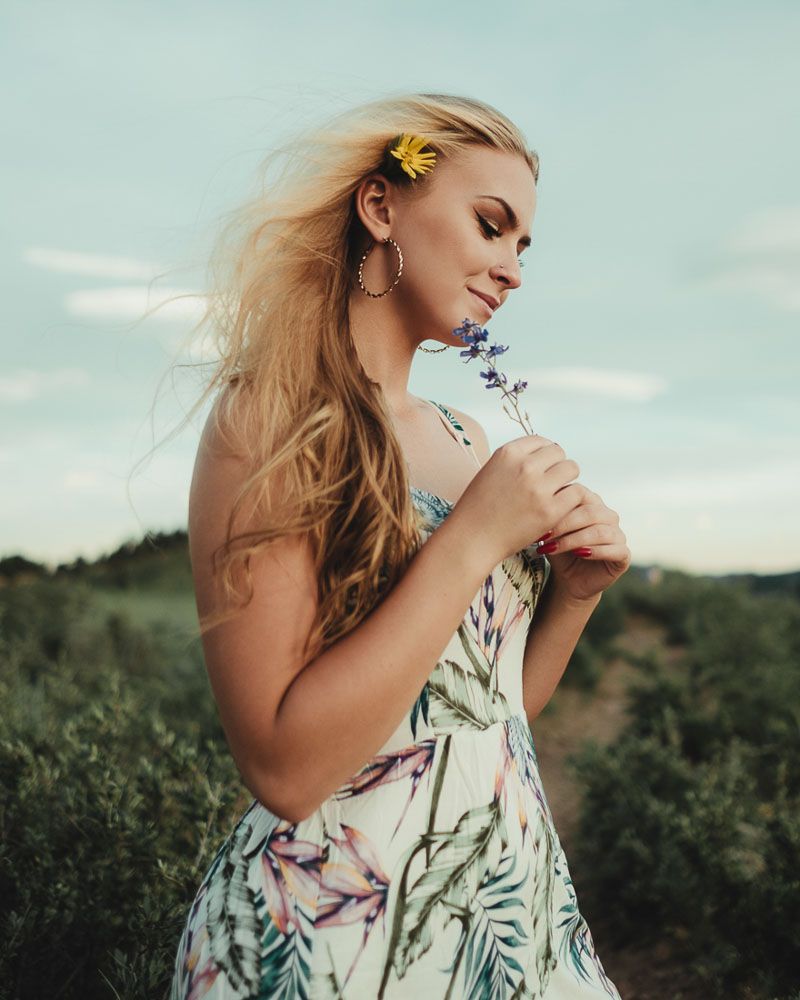 Ethereal summer portrait with floral dress and flowing hair in natural setting.