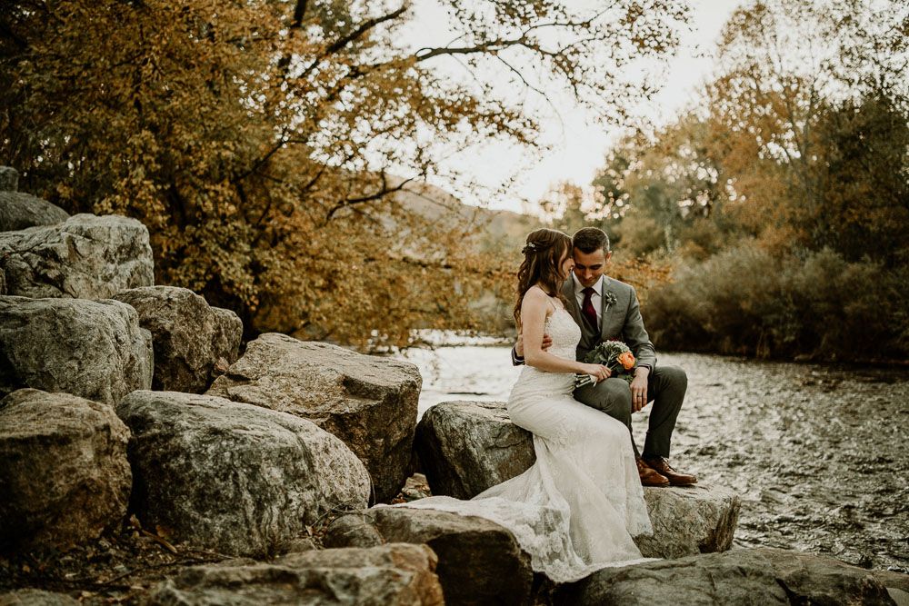 A romantic wedding photo session on rocky terrain surrounded by autumn trees.