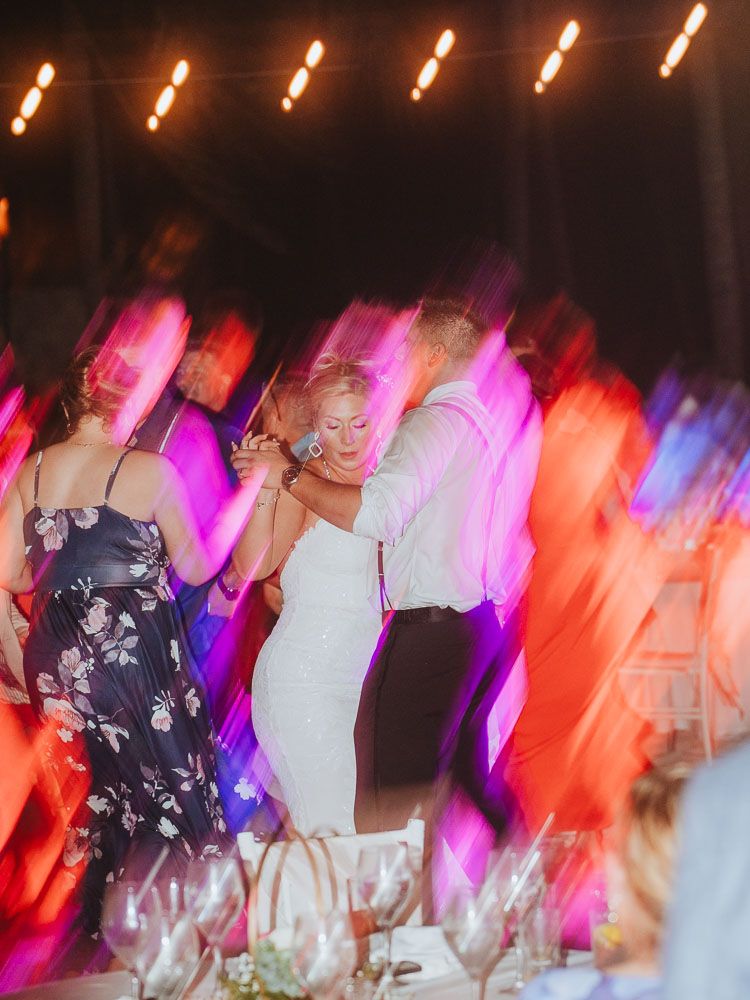 Abstract motion blur of wedding dancers under colorful pink and orange lighting.