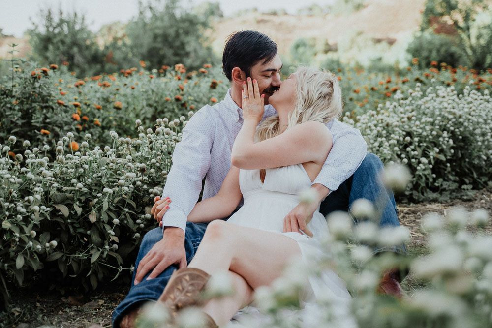 Intimate moment captured between couple in flowering garden setting.