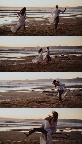 Couple in white dresses playfully dance and spin on a sunset beach with waves rolling in the background.