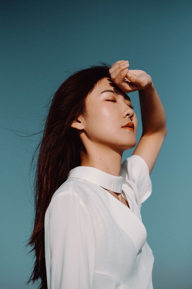 Profile portrait against teal background with dramatic lighting and white shirt.