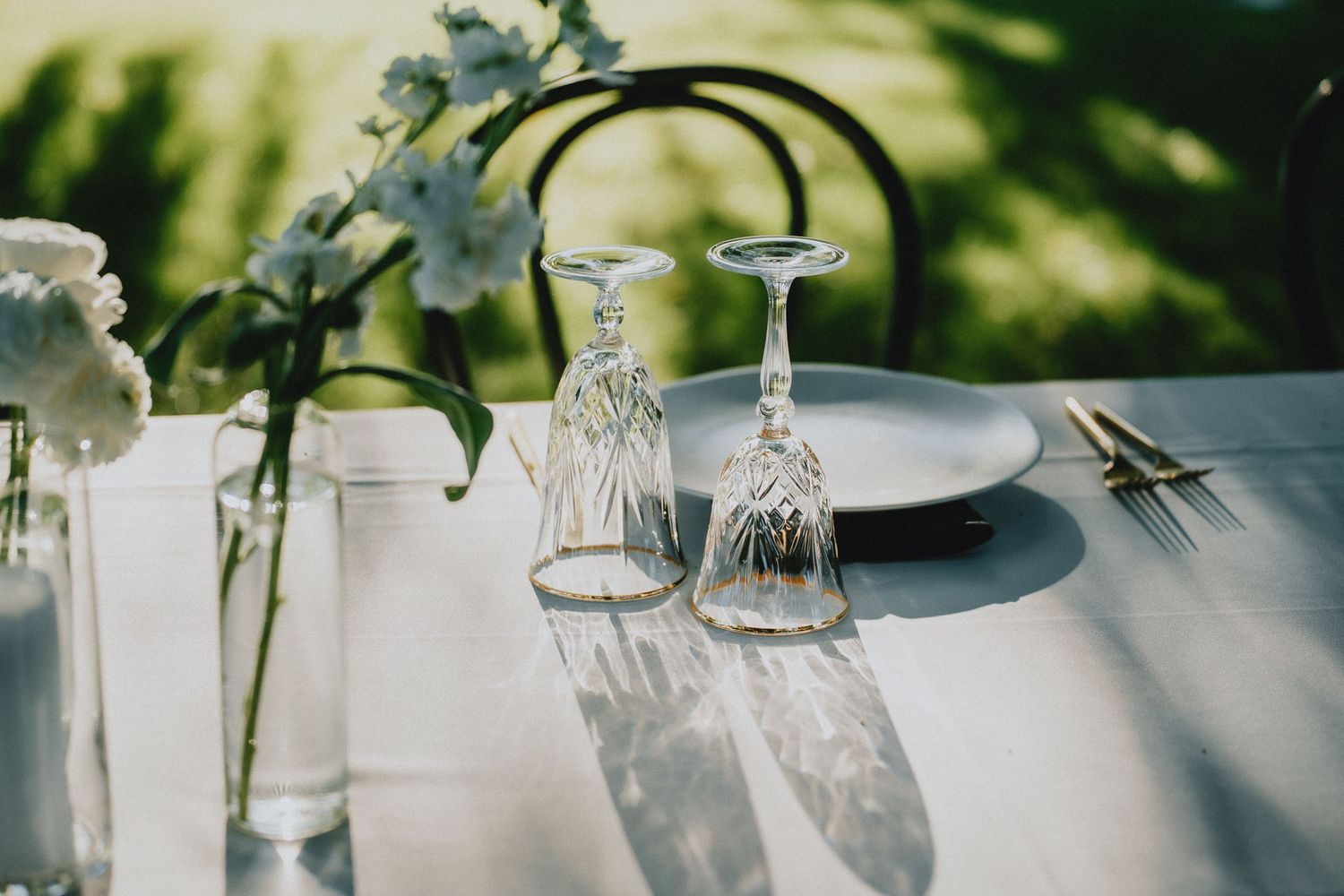 Elegant table setting with upturned wine glasses and delicate flower arrangements.