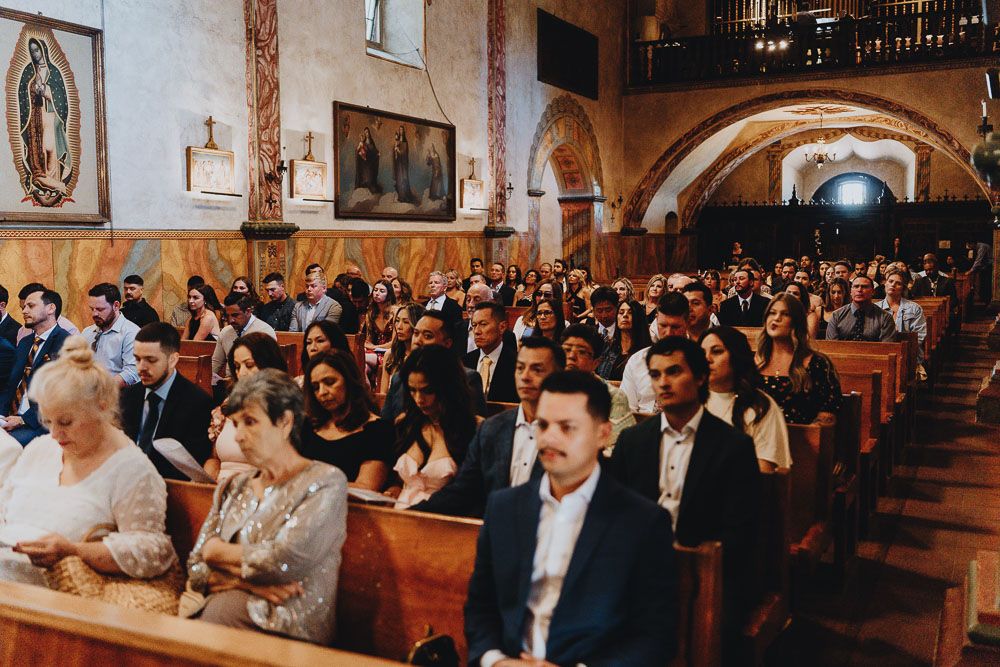 Wedding guests seated in traditional church pews during ceremony.