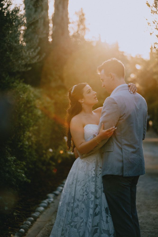 A couple embraces on a garden path during golden hour wedding photography.
