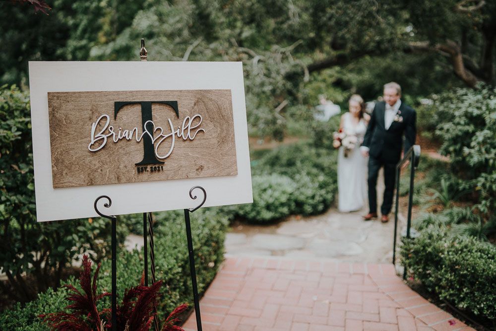 Wedding ceremony signage and decorative elements displayed along a garden pathway.