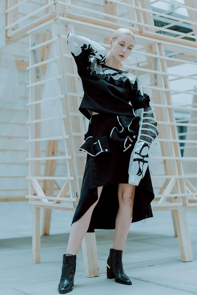Modern fashion shoot featuring black and white graphic clothing against industrial background.