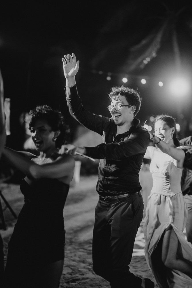 Dancing partygoers on an outdoor dance floor with joyful expressions at night.