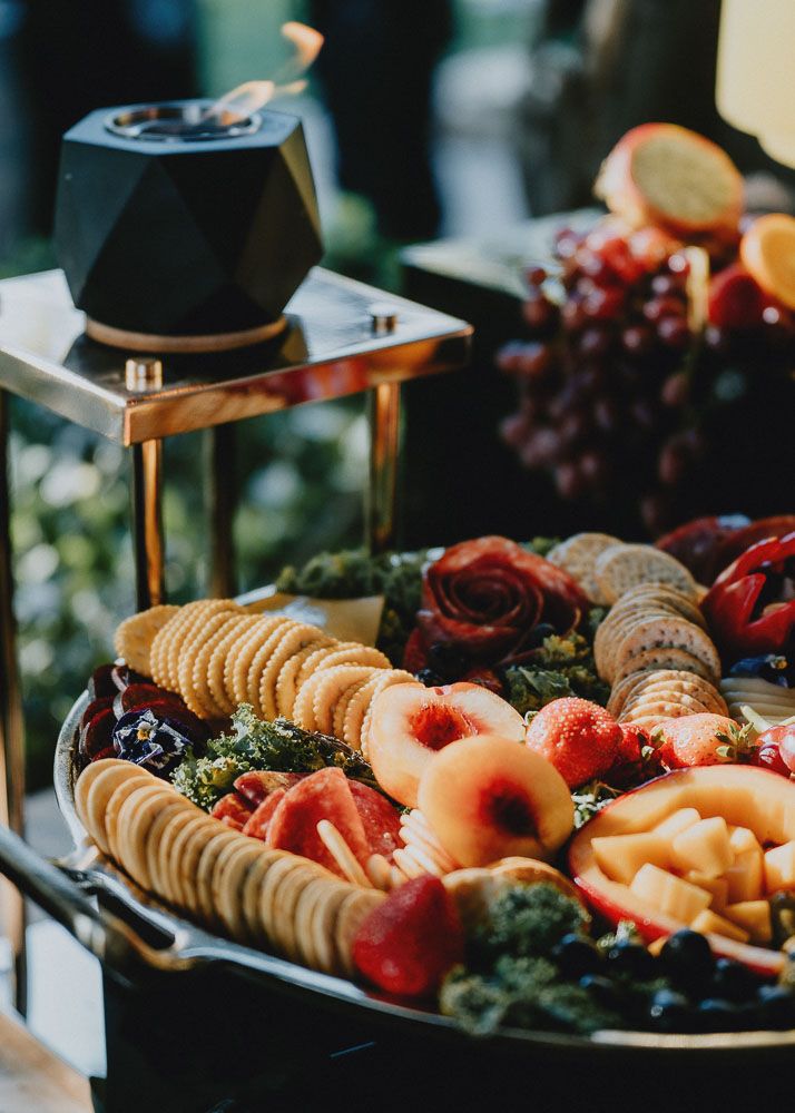 Gourmet charcuterie board with fresh fruits, crackers and meats at catered event.
