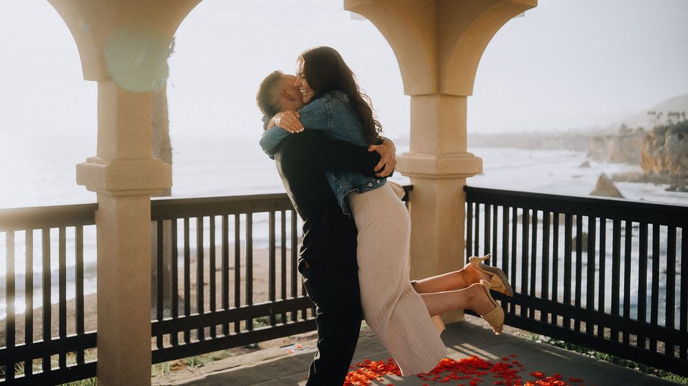 Sweet celebration moments after a proposal on a columned balcony.