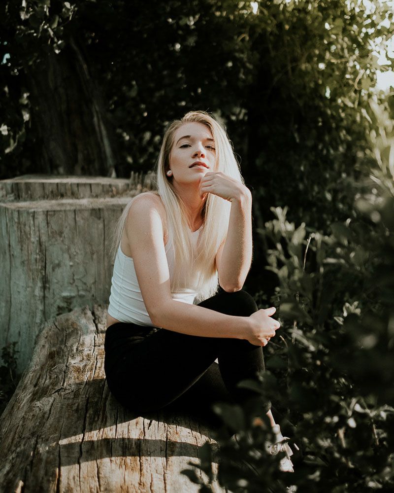 Candid outdoor portrait on tree stump in casual attire.