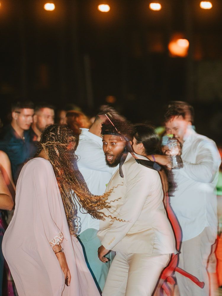Wedding guests dancing in elegant attire at an evening reception.
