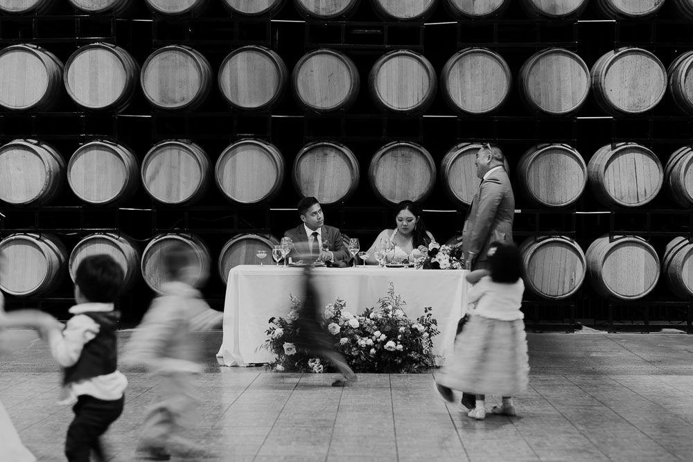 Wedding reception venue with wine barrels and elegant table settings.