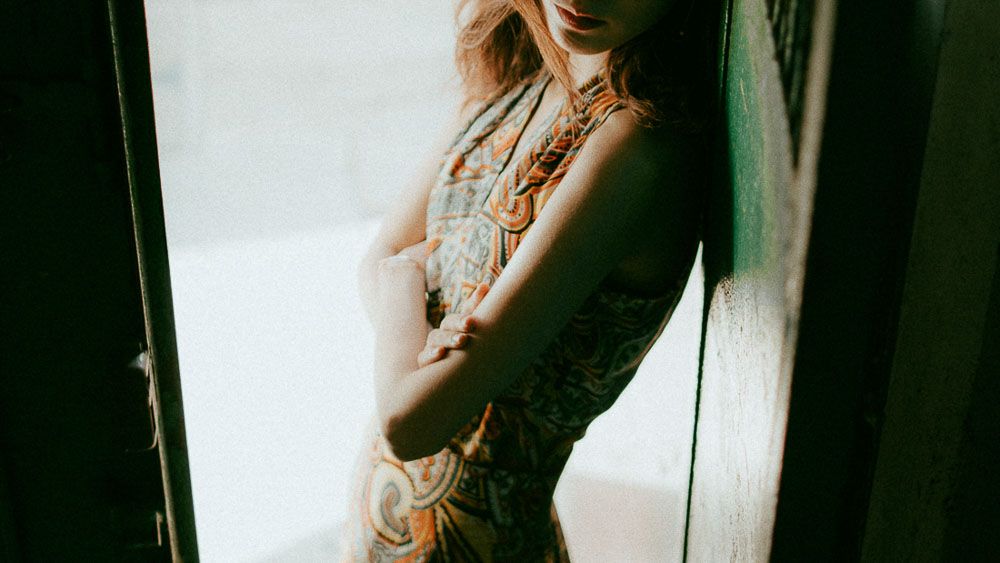 Artistic silhouette fashion photo showing intricate dress pattern in dramatic lighting.