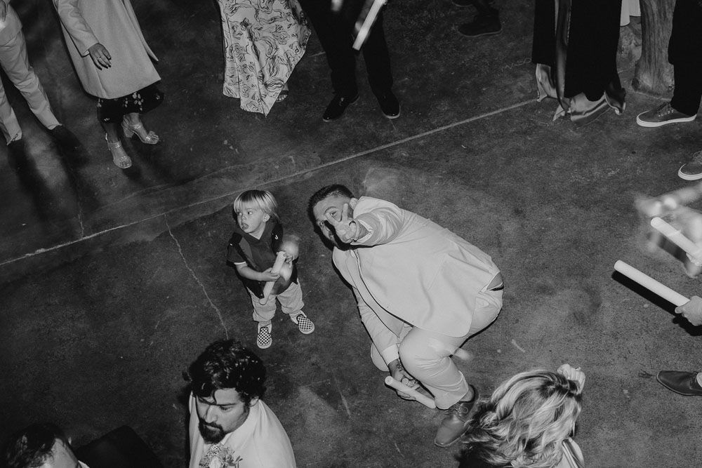 Black and white overhead view of guests dancing and celebrating on a reception dance floor.