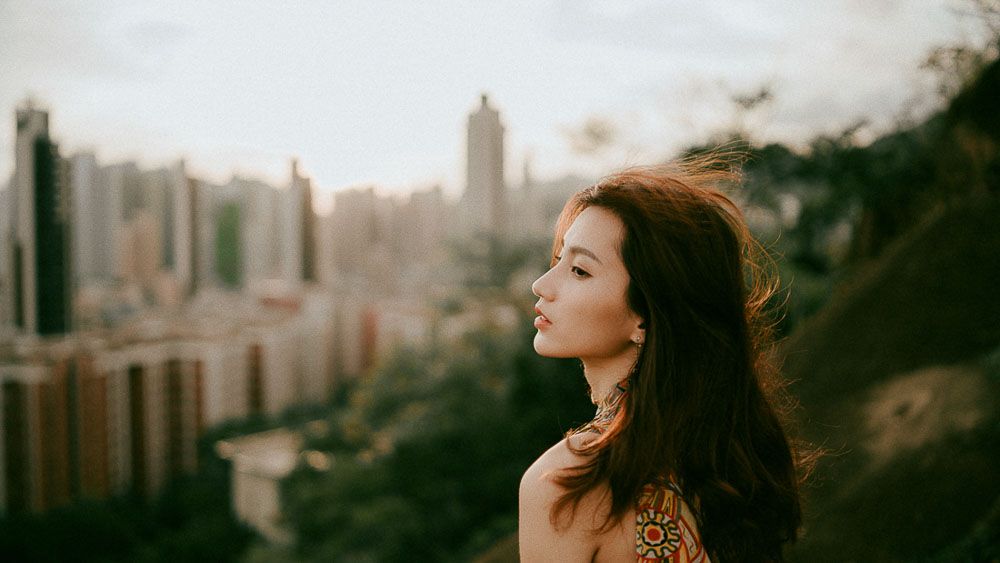 Fashion portrait against a cityscape backdrop during golden hour.