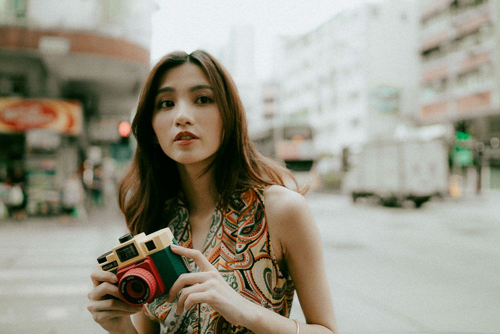 Street photography scene with vintage camera and patterned dress in urban setting.