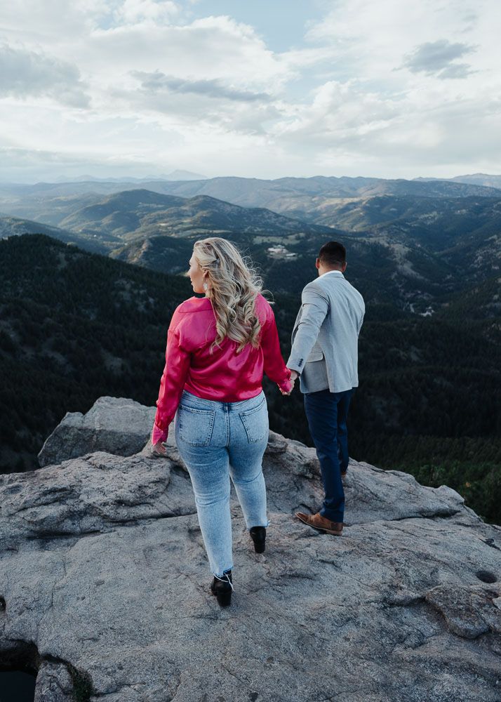 Couple exploring rocky mountain overlook with dramatic landscape views.